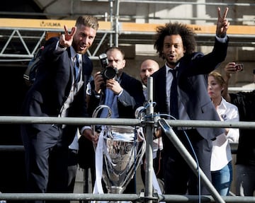Los jugadores del Real Madrid, Sergio Ramos (i) y el brasileño Marcelo, ofrecen el trofeo de Liga de Campeones a los aficionados blancos concentrados en la Puerta del Sol, tras la visita del equipo madridista a la sede de la Comunidad de Madrid.
