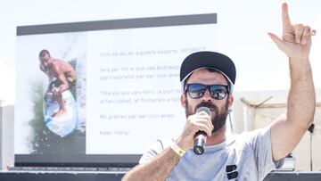 Quim Garcia, director deportivo del Extreme Barcelona, con gafas de sol, gorra y camiseta gris, habla con un micrófono inhalámbrico mientras levanta un dedo dirigiéndose al público. Al fondo, una presentación con letras