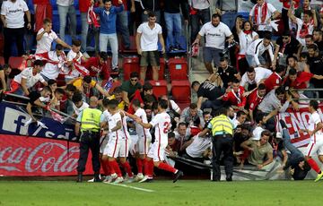 Aficionados del Sevilla caen tras ceder una de las vallas en la celebración del segundo gol del equipo andaluz, durante el encuentro correspondiente a la séptima jornada de primera división que disputan esta tarde frente al Eibar en el estadio de Ipurúa,