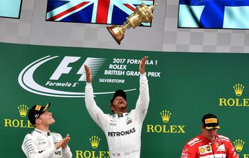 Lewis Hamilton lanza al aire el trofeo en el podio. Junto a él, Valtteri Bottas y Kimi Raikkonen.