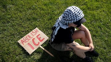 Un manifestante se sienta con un cartel que dice "Abolir ICE" durante una protesta en Hamilton, Ohio.