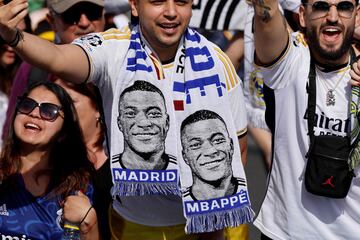 Supporters wearing football scarves depicting French footballer Kylian Mbappe cheer 