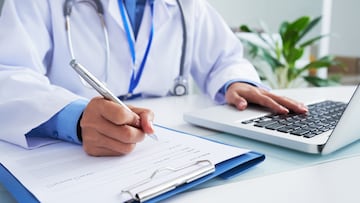 Doctor checking information in computer program before filling medical card