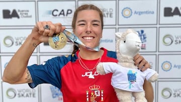 La patinadora Mery Mu&ntilde;oz mostrando su medalla de oro en los World Skate Games 2022 de Argentina, lograda en Roller Freestyle Street. Con la mascota y el photocall detr&aacute;s. 