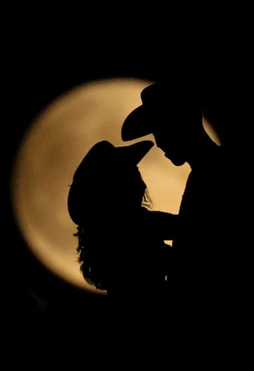 Personas silueteadas contra la luna llena el día del eclipse lunar en las Dunas de Samalayuca, en las afueras de Ciudad Juárez, México.