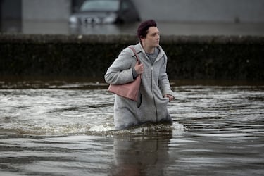 Una mujer intenta caminar a través del agua después de las fuertes lluvias en Ciaran, en el centro de la ciudad de Newry, Irlanda del Norte.