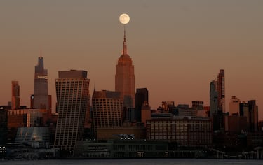 La luna se alza tras el Empire State Building al atardecer en la ciudad de Nueva York.