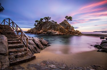 Las playas de l’Ampolla forman parte indiscutible de la riqueza natural del pueblo y no es por casualidad. Uno de los mejores ejemplos lo representa la playa Cap-Roig donde el verde de los pinares se mezcla con el azul de las aguas y el reflejo rojo de los acantilados, que dan nombre a la playa. En el fondo, se intuye la línea del horizonte rota, de vez en cuando, por la estela de un barco que se pasea mar adentro.