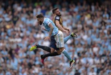 El jugador francés del Arsenal, Giroud, y el defensa argentino del Manchester City, Otamendi, parecen llevar caminos distintos en un salto, aunque parece que ninguno se lleva el balón.