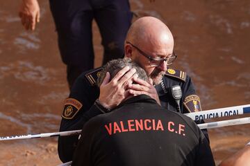 Miembros de la policía local reaccionan ante la noticia de la muerte de uno de sus compañeros en las inundaciones en Valencia, España.