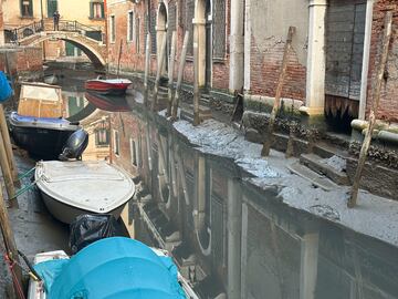 Barcos atracados en un canal seco durante la marea baja en la ciudad laguna de Venecia, Italia.