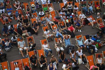 La gente sentada en sillas cómodas mientras ven los partidos de Roland Garros en la pantalla gigante de la pista principal.