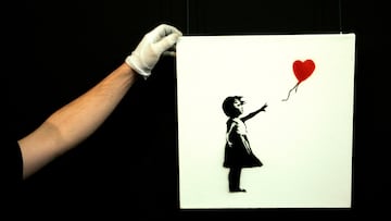 FILE PHOTO: A gallery technician adjusts Banksy's artwork "Balloon Girl" (1975) at Sotheby's auction house at Olympia in London February 2, 2007. The piece is expected to fetch between $14,000 - $20,000 when it is auctioned on February 7. REUTERS / Luke MacGregor (BRITAIN)/File Photo