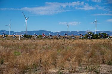 El pelotón pasa junto a aerogeneradores durante la octava etapa de la Vuelta a España.