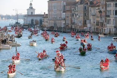Personas vestidas de Papá Noel reman durantela  regata navideña en el Gran Canal de Venecia.