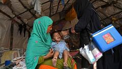 A health worker (R) administers polio vaccine drops to a child during a polio vaccination door-to-door campaign in LahorexA0on August 16, 2020. (Photo by Arif ALI / AFP)