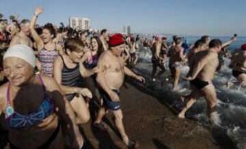 Decenas de ciudadanos participaron este mediodía en el tradicional primer baño del año en la playa de Sant Sebastià del barcelonés barrio de la Barceloneta.