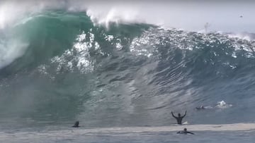Un surfista levanta los brazos y otros reman para escapar de una ola gigante en The Wedge, Orange County (California, Estados Unidos).