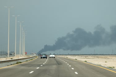 Los vehículos se mueven por una carretera mientras se elevan columnas de humo desde la refinería de petróleo Ras Tanura.