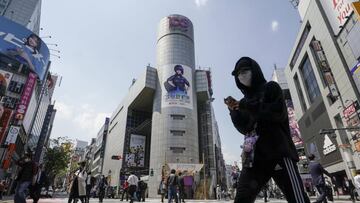 Un joven japonés camina por el centro de la ciudad con un móvil en sus manos.