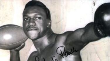 Charlie "Chuck" Powell con guante de boxeo y balón de fútbol americano.