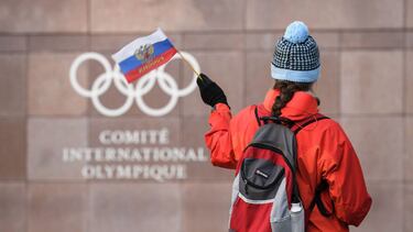 (FILES) In this file photograph taken on December 5, 2017, a supporter waves a Russian flag in front of the logo of the International Olympic Committee (IOC) at their headquarters in Pully near Lausanne. - The World Anti-Doping Agency on December 9, 2019,