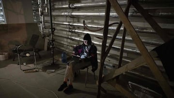 A resident uses a computer in a residential building that was hit by debris from a downed rocket in Kyiv on March 20, 2022.