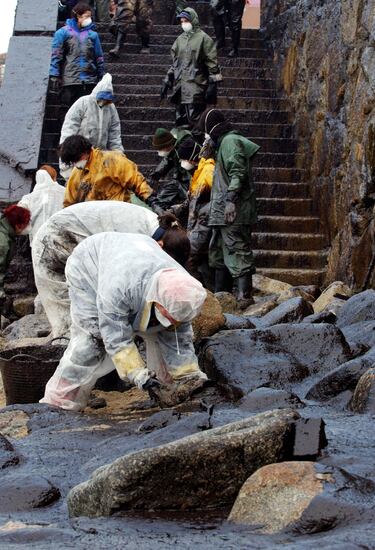 Voluntarios y trabajadores recogen el fuel de las playas. 