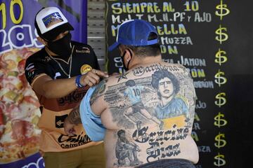 Guillermo Rodríguez, bautizado en la iglesia maradoniana, muestra los tatuajes en su espalda que representan
a la leyenda del fútbol argentino Diego Maradona, junto a su hijo Axel, en su pizzería llamada Siempre al 10,
en honor al número que lucía su ídolo en su camiseta, en Merlo (Buenos Aires).