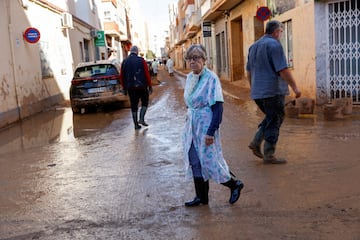 Una mujer camina por una calle embarrada tras las inundaciones en Catarroja, Valencia, España.