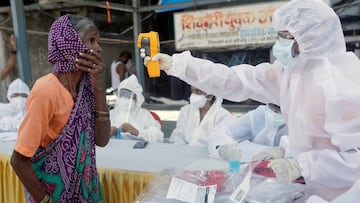 A health-worker wearing personal protective equipment (PPE) checks the temperature of a woman using an electric thermometer during a check-up campaign for the coronavirus disease (COVID-19), at a slum area in Mumbai, India June 29, 2020. REUTERS/Francis M