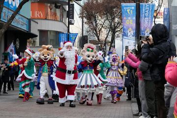 Un artista, en el centro, vestido con un disfraz de Pap¨¢ Noel, marcha con otros durante un evento callejero para promover el festival navide?o de un parque de diversiones en el centro de Se¨²l, Corea del Sur.