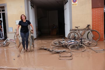 Una mujer saca sillas plegables cubiertas de barro después de que las lluvias torrenciales provocaran inundaciones en La Alcudia, región de Valencia.