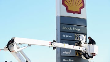 An electrical contractor repairs a sign with gasoline fuel prices above six and seven dollars a gallon at the Shell gas station.