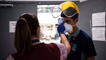 A health worker checks the body temperature of an employee at Santiago International Airport, in Santiago, on April 20, 2020 during the new coronavirus, COVID-19, pandemic. - Latin America&#039;s biggest airline, the Brazilian-Chilean group LATAM, announced last Friday that the 95% reduction of its passenger operations announced in April will be extended until May due to the coronavirus crisis, which will cause a deeper impact than expected. (Photo by MARTIN BERNETTI / AFP)