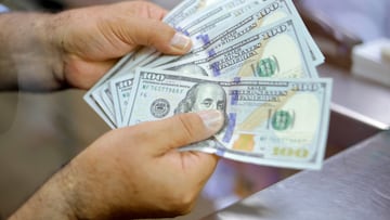 Billetes de cien dólares en la ventanilla de un banco