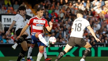 El delantero del Granada Lucas Boyé (c) disputa una posesión ante el centrocampista del Valencia Pepelu (d).