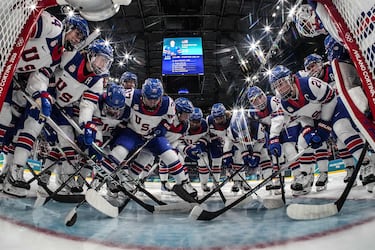 Las jugadoras de EE. UU. se reúnen en el poste de la portería antes del partido de hockey sobre hielo del Grupo A de la ronda preliminar femenina entre Canadá y EE. UU.