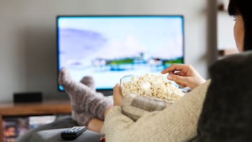 Persona viendo la tv mientras come palomitas