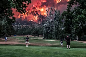 El incendio forestal de Eagle Creek arde, mientras los golfistas juegan en el campo de golf Beacon Rock en North Bonneville, Washington, EE.UU
