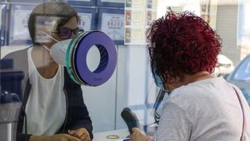 Una lotera atiende a una clienta