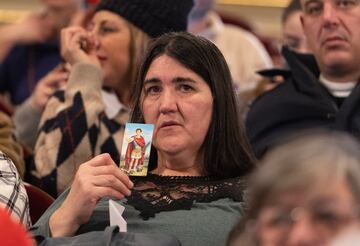 Una mujer sujeta la foto de una virgen durante la celebración del Sorteo Extraordinario de la Lotería de Navidad 2023.