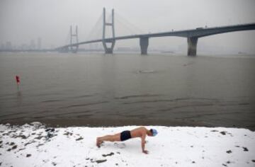 Un nadador hace flexiones en las orillas cubiertas de nieve del río Yangtsé, en Wuhan, provincia de Hubei