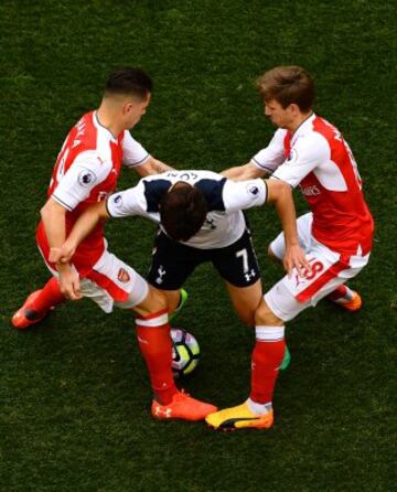 Los jugadores del Arsenal, Granit Xhaka y Nacho Monreal, intentan quitarle la posesión del balón a Heung-Min Son del Tottenham Hotspur.