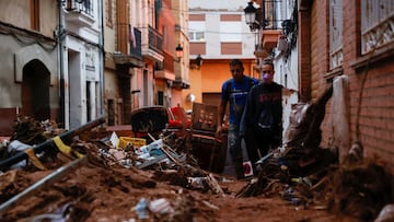 People walk through mud in a street, following heavy rains that caused floods, in Paiporta, near Valencia, Spain, November 4, 2024. REUTERS/Eva Manez