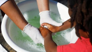 A volunteer helps a child wash her hands at a school feeding scheme during a nationwide lockdown aimed at limiting the spread of the coronavirus disease (COVID-19) in Blue Downs township near Cape Town, South Africa, May 4, 2020. Picture taken May 4, 2020