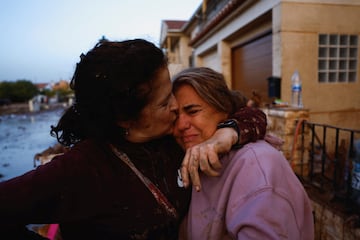 Eva Defez, de 50 años, recibe el abrazo de una amiga a la puerta de su casa tras pasar la noche atrapada en su casa con su familia debido a las inundaciones en Utiel,.