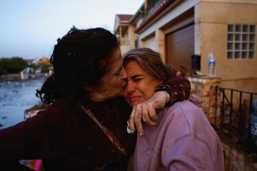 Eva Defez, de 50 años, recibe el abrazo de una amiga a la puerta de su casa tras pasar la noche atrapada en su casa con su familia debido a las inundaciones en Utiel,.