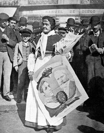 En una céntrica de Madrid, una mujer vende periódicos e imágenes populares durante la llegada del presidente Émile Loubet a España. Loubet fue un político y estadista francés, séptimo presidente de la República sa durante la Tercera República.