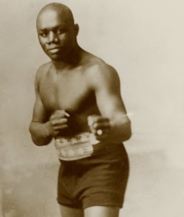 Jack Johnson (1878-1946) fue el negro más famoso del mundo durante más de siete años. Los que 'El gigante de Galveston' pasó como campeón del mundo de los pesos pesados (1908-1915). Un trono al que ningún púgil negro había subido. Tanto dolió, que el escritor Jack London alentó el advenimiento de 'La Gran Esperanza Blanca' que rescatara el cinturón para los blancos. Caricaturizado como un mono en muchas ocasiones, tuvo que hacer frente a un racismo secular (él fue hijo de esclavos) e institucionalizado. En 1913 fue detenido bajo el cargo de pasar la frontera de Illinois con una mujer (blanca, que luego sería su esposa), acusado de tráfico de prostitutas. Ese fue el parapeto que encontraron para destruirle. Se le condenó a un año de prisión que no cumplió, porque huyó del país y siguió boxeando fuera. En 2018, Donald Trump firmó su perdón presidencial y restituyó su honor... un poco tarde. 